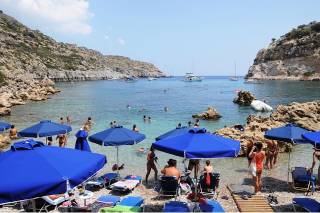Människor solar och badar på strand i Grekland