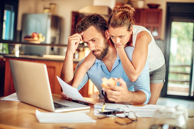 Ett ungt par sitter framför en laptop och ser över sin ekonomi.